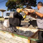 Trabalhadores da limpeza urbana esvaziam lixeiras em uma área da cidade.