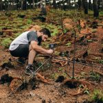 Pesquisador instala equipamentos para realizar pesquisa ambiental em uma área de vegetação.