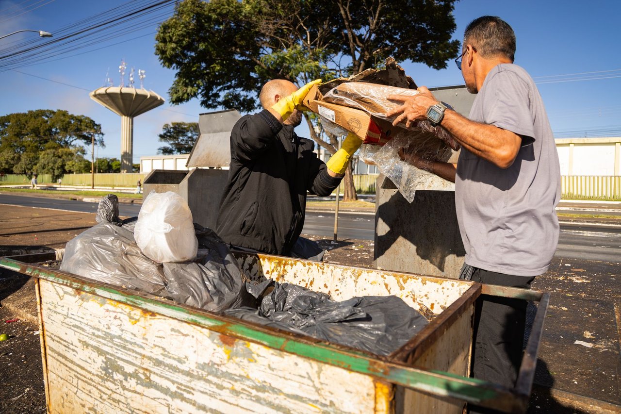 Trabalhadores da limpeza urbana esvaziam lixeiras em uma área da cidade.