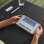 Pessoa utiliza um tablet para consultar informações de registro eleitoral em uma estação de votação.