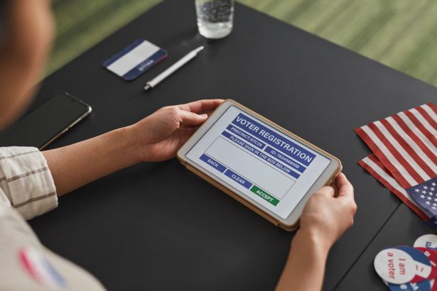 Pessoa utiliza um tablet para consultar informações de registro eleitoral em uma estação de votação.
