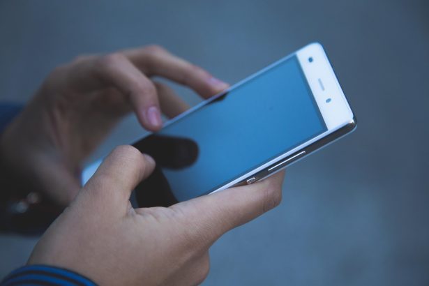 Mãos segurando e utilizando um smartphone, sem texto legível na tela.